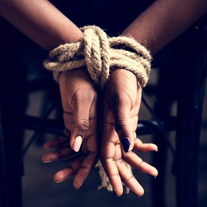 Zwei Hände auf den Rücken einer Person zusammengebunden