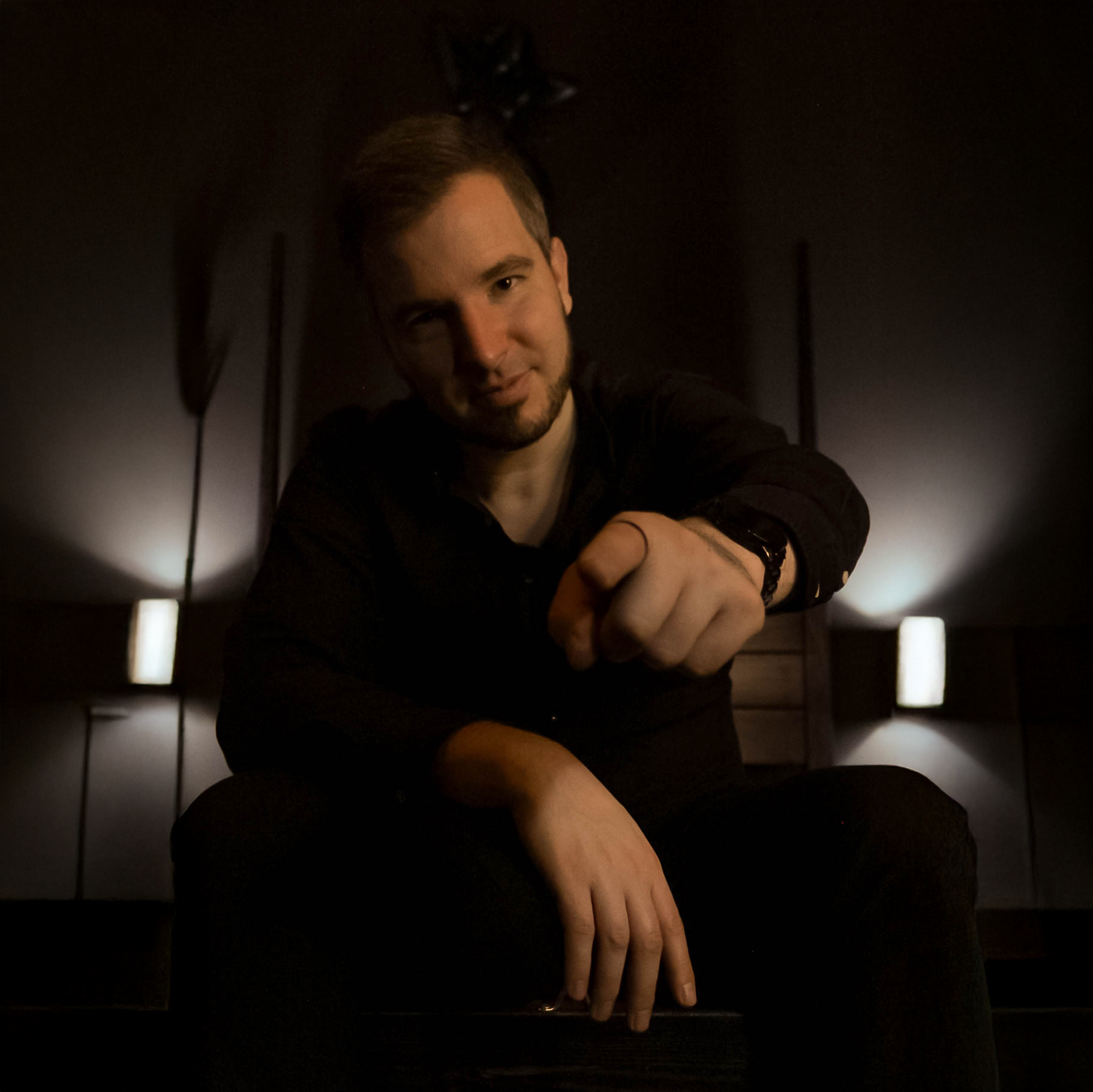 Mentor Chris sitzt auf dem Bett, zeigt mit dem Finger auf die Kamera welche vor ihm und leicht unterhalb ist.